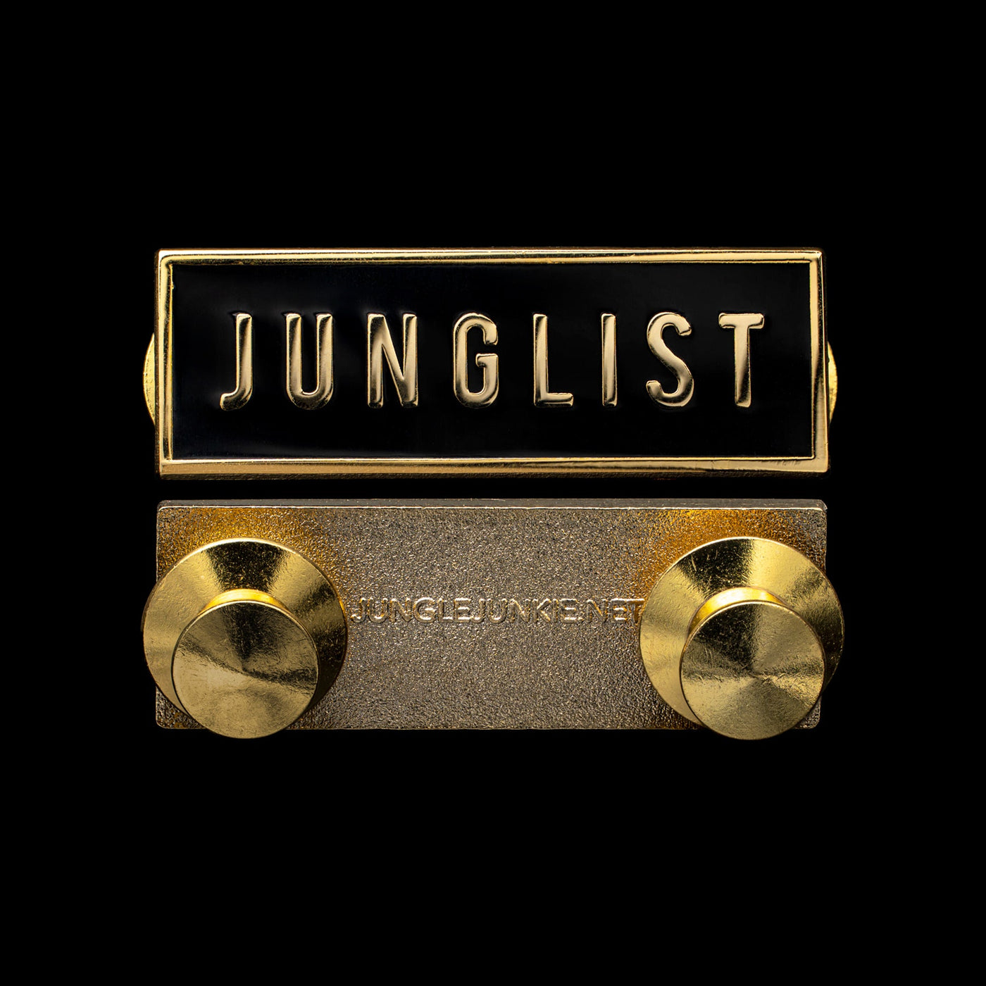 Front and Back view of Small Rectangular Gold Metal Pin with Black Enamel Face and two Circular Locking Fasteners on back of pin. Text on front of pin reads, J-U-N-G-L-I-S-T. Text on back of pin reads, jungle junkie dot net.